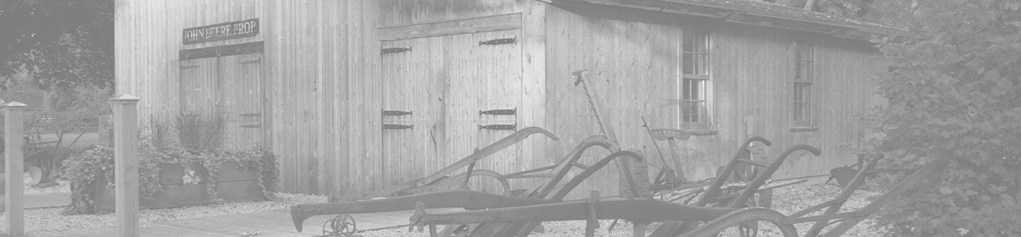 Tonirana crno-bijela fotografija simulacije originalne kovačnice tvrtke John Deere na zelenoj pozadini