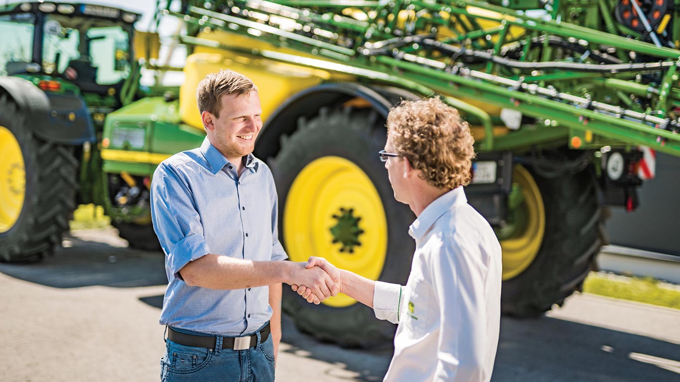 Rukovanje zastupnika i kupca ispred John Deere prskalice