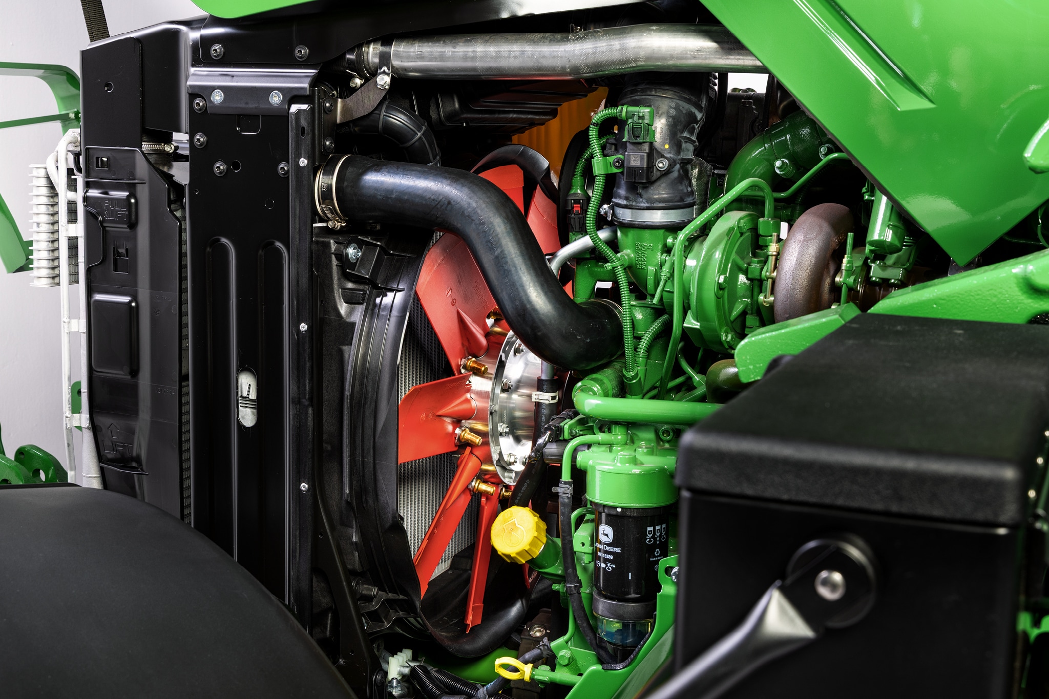 Prikaz motornog prostora traktora John Deere serije 6M izbliza na kojem su naglašeni sustav hlađenja i komponente motora.