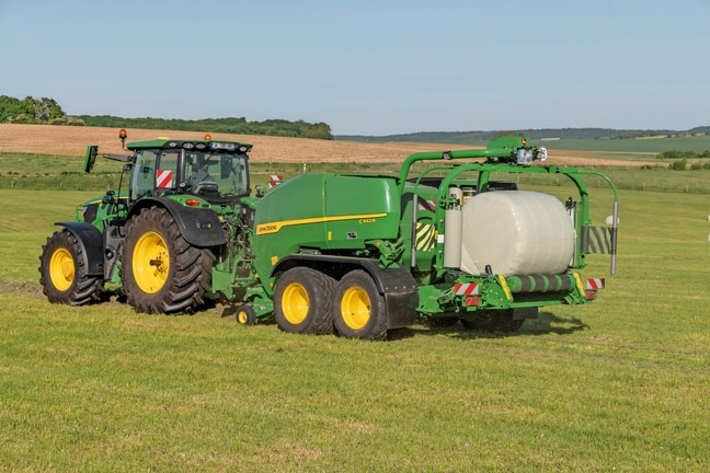 John Deere C442R balirka s omatanjem koju vuče John Deere 6R 185 i koja izrađuje silažne bale velike gustoće
