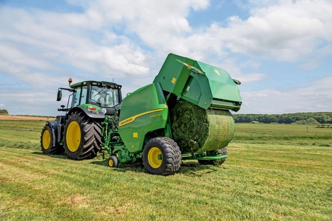 John Deere F442M balirka koju vuče traktor John Deere 6M koji izbacuje balu trave