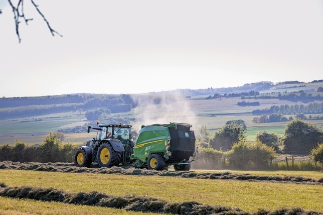 John Deere V462R kojeg vuče traktor John Deere 6R 185 za baliranje sijena